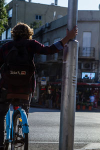 Rear view of woman with bicycle on street in city