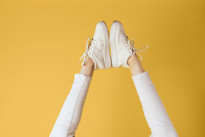 Low section of woman standing against yellow background