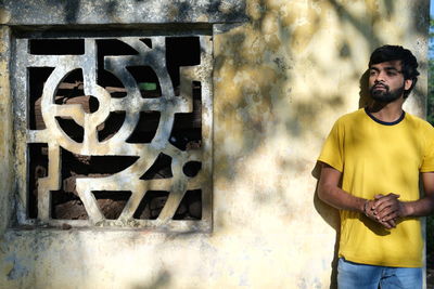 Portrait of young man standing against wall