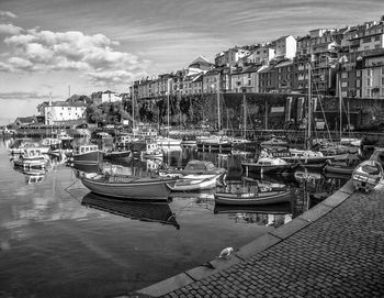 Boats moored at harbor in sea against sky