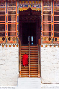 Rear view of monk walking on monastery steps