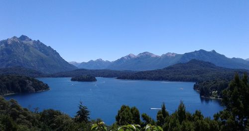 Scenic view of lake and mountains against clear blue sky