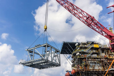 Low angle view of crane at construction site against sky