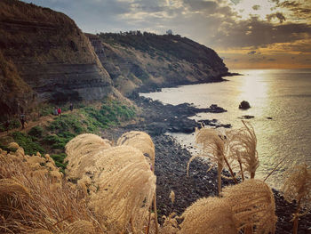 Rocks by sea against sky during sunset