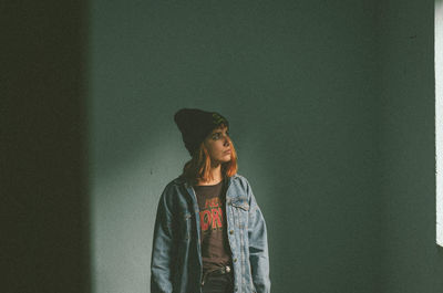 Young woman standing against wall