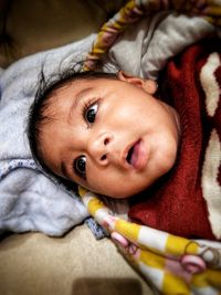 Close-up of cute baby looking away while lying on bed