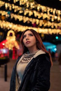 Portrait of young woman in city at night