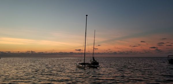 Sailboat in sea against sky during sunset