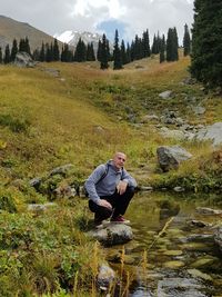 Rear view of man in stream amidst trees