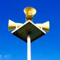 Low angle view of road sign against clear blue sky