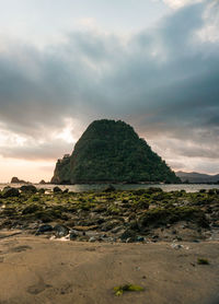 Rock formation on beach against sky