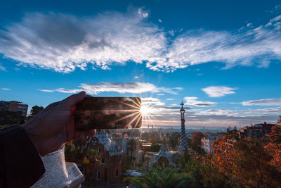 Hand holding cityscape against sky