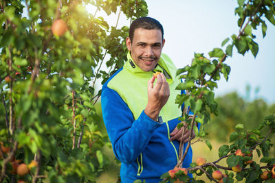 Portrait of smiling young woman standing against plants