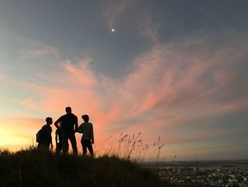 Silhouette people standing on beach against sky during sunset