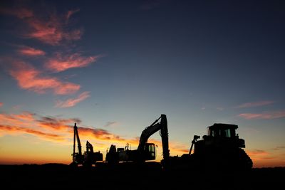 Silhouette construction site against sky during sunset