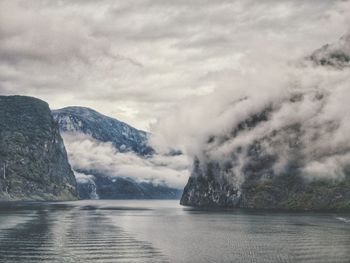 Scenic view of sea by mountain against sky