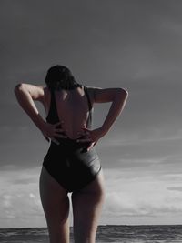 Rear view of young woman standing at beach