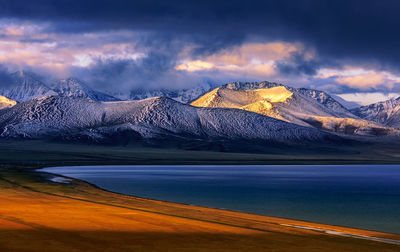 Scenic view of lake against cloudy sky during sunset