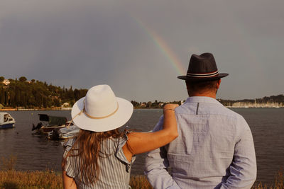 A woman and a man watching sea and rainbow