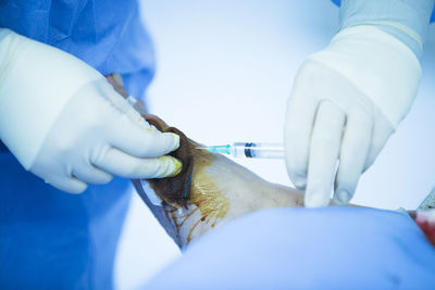 Close-up of doctor injecting syringe in patient foot in operating room