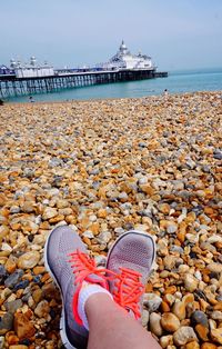 Low section of woman relaxing at beach against eastbourne pier