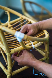 Close-up of man making wicker chair