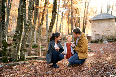 Side view of mother and daughter standing in forest