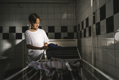 Boy doing laundry in utility room