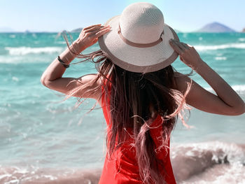 Rear view of woman wearing hat looking at sea