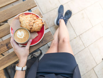 Low section of woman holding coffee cup outdoors