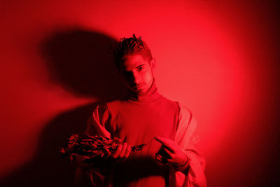 Portrait of man holding red flowers against red background