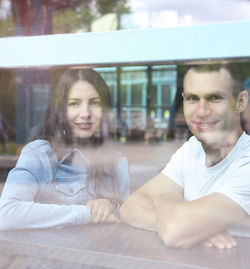 Portrait of smiling woman with reflection on window