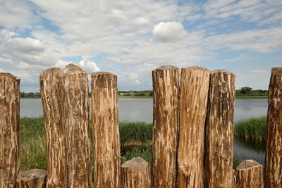 Panoramic shot of wooden post on landscape against sky