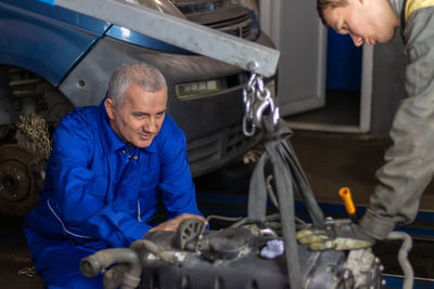 Photo of diesel engine. an experienced mechanic and his colleague observe  condition of the engine
