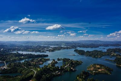 High angle view of sea and landscape against blue sky