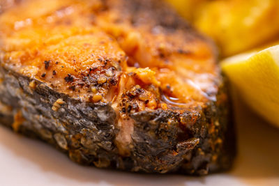 Close-up of a grilled salmon chop with crispy skin and crushed pepper