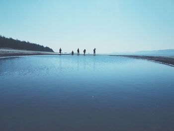 People on shore against clear sky