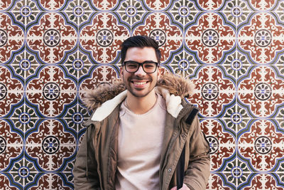 Portrait of young man standing against wall