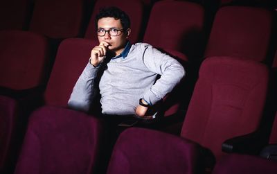 Young man looking away while sitting on seat