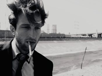 Close-up of young man smoking against sky