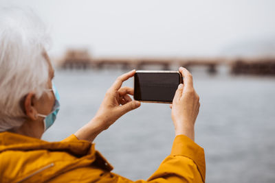 Side view of woman using mobile phone against sky