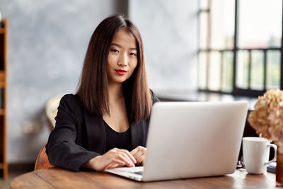 Portrait of woman using phone while sitting on table