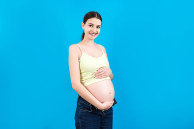 Portrait of a smiling young woman against blue background