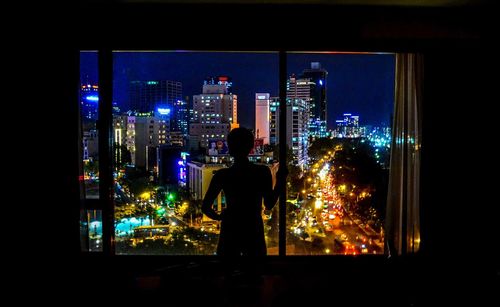 Silhouette of woman standing in illuminated city at night