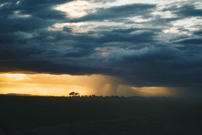 Scenic view of dramatic sky over silhouette field