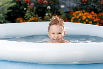 Happy white toddler playing in the pool in the garden. 