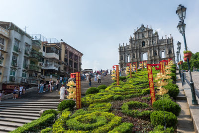 People on street amidst buildings in city against sky