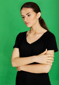 Portrait of beautiful young woman against green background