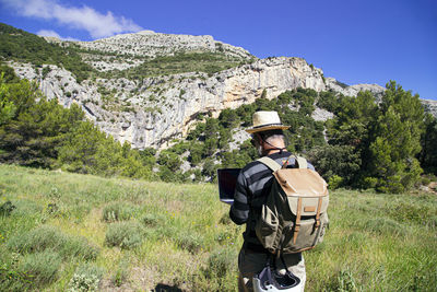 Man standing by plants on land against mountains