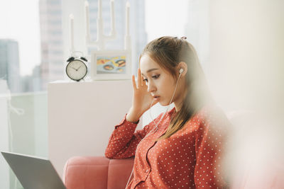 Young woman looking away while sitting at home